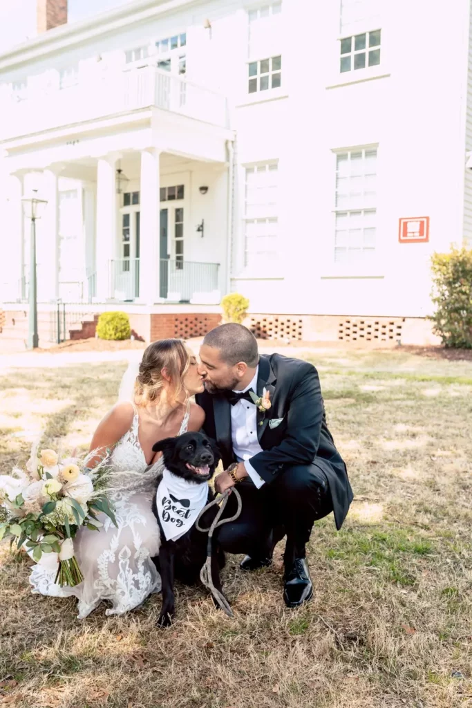bride and groom with their dog wearing a vest which reads "Best Dog"