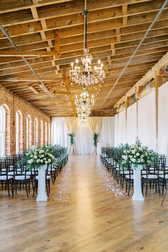 flower-topped pillars in front of indoor wedding aisle