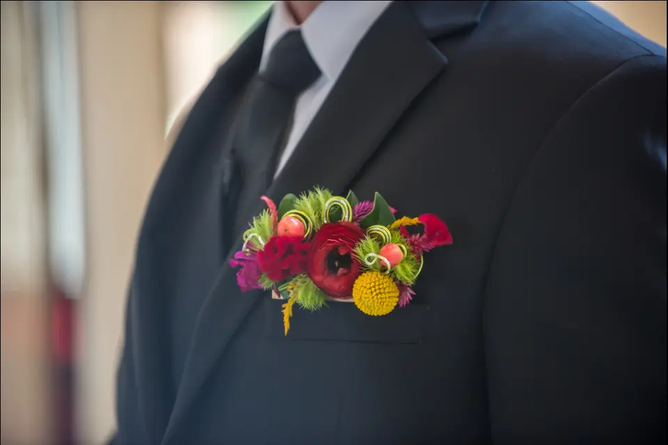 colorful boutonnière pinned to a man's wedding coat breast pocket